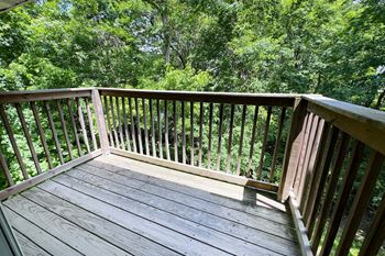 A wooden deck with a railing overlooking a green forest.